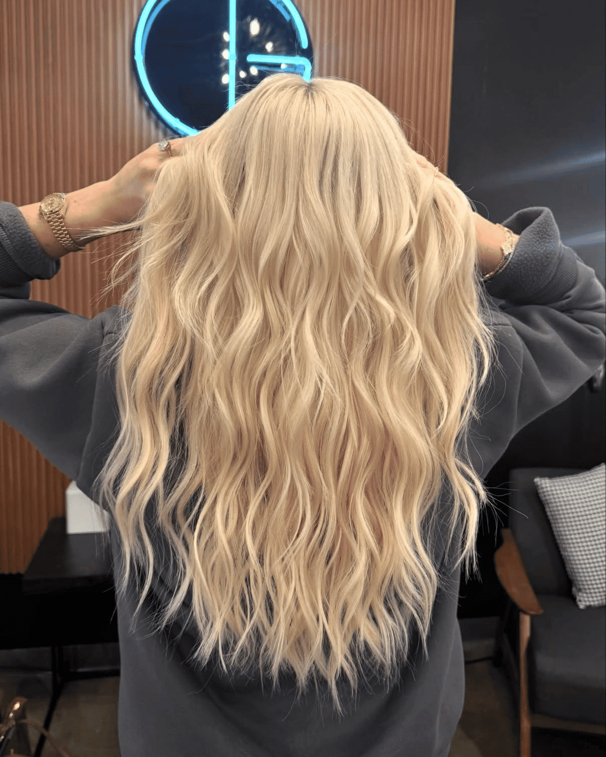 Blonde-haired person in a salon, with wavy, styled hair viewed from the back.