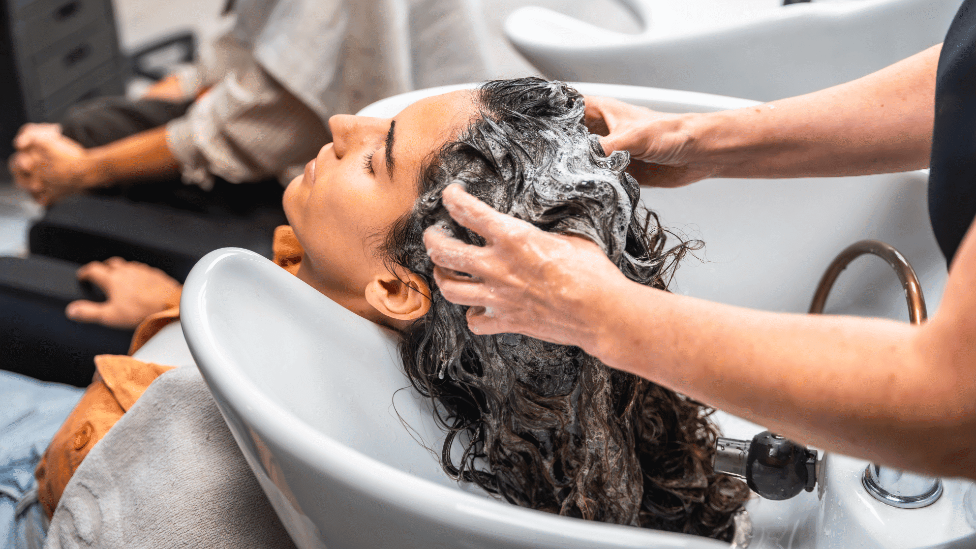 Person getting hair washed at a salon sink.