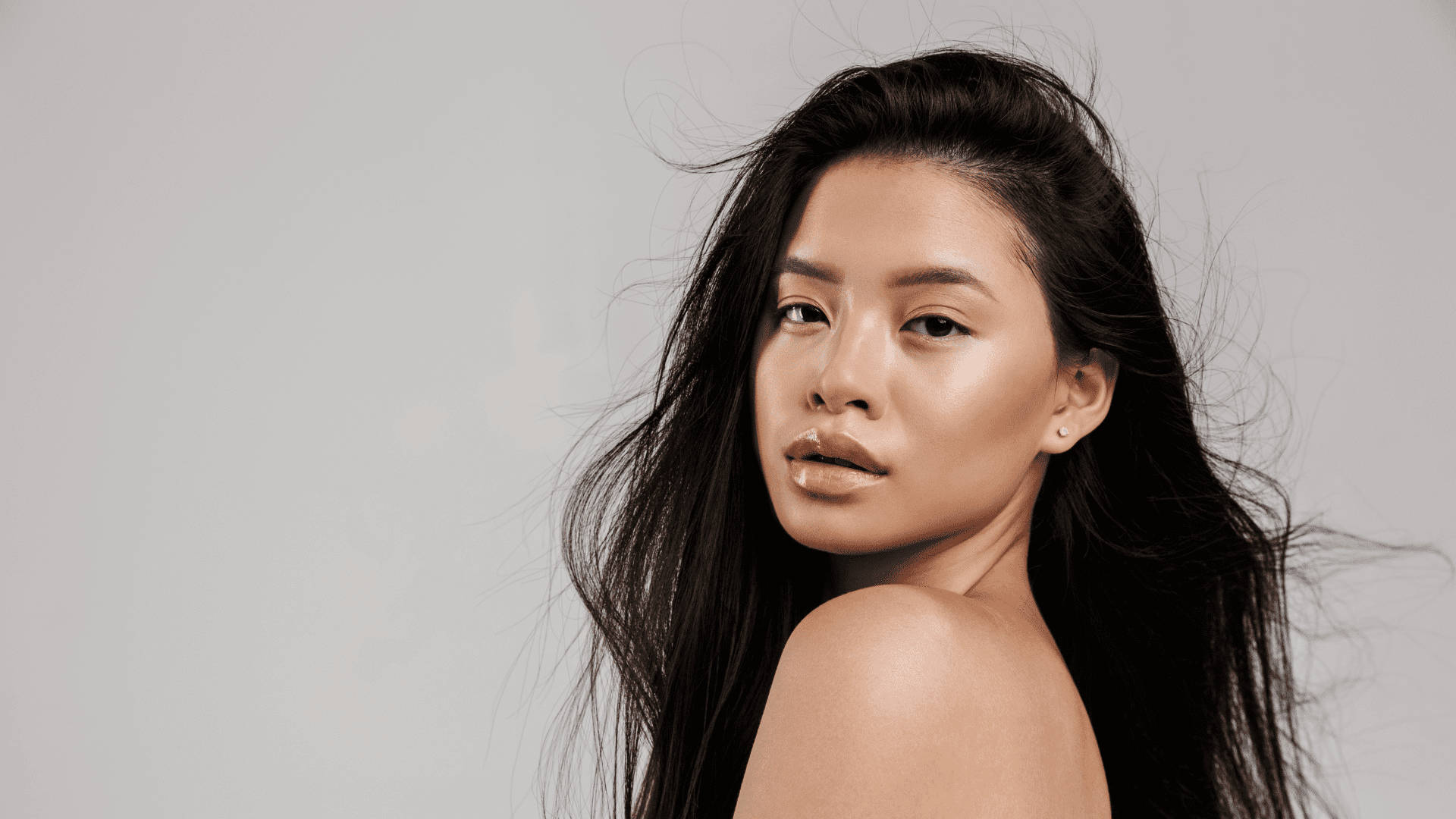 Confident woman with flowing black hair against a neutral background.
